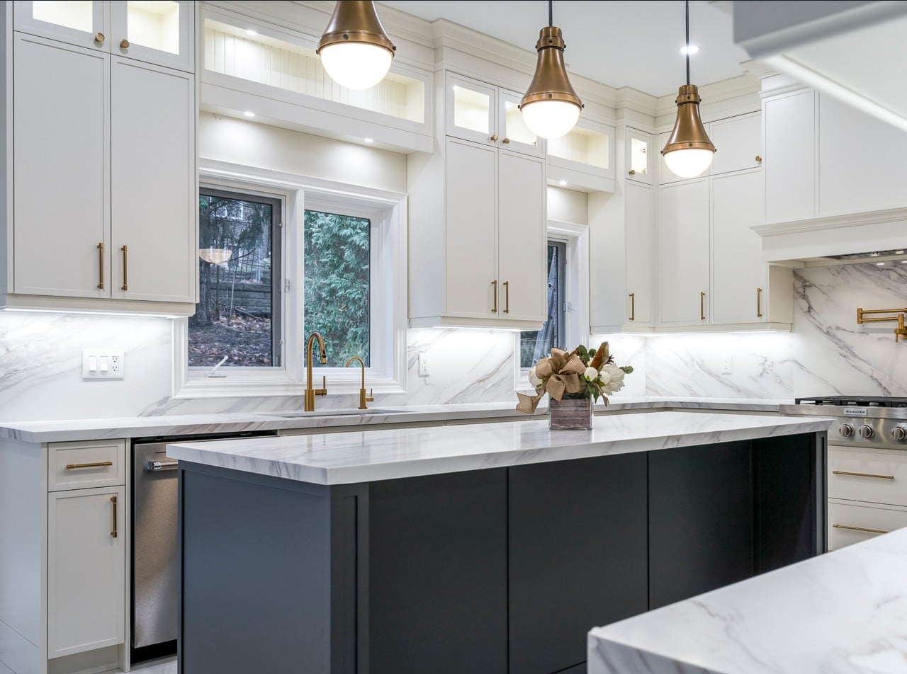 A kitchen with white cabinets and marble counter tops