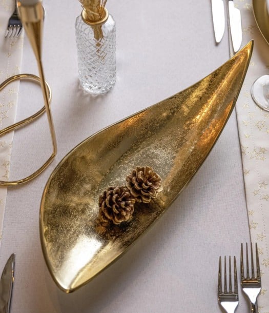 Gold decorative bowl with two pine cones on table setting